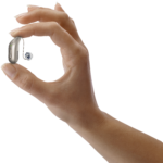 Oticon_Intent_miniRITE_Left_C090ChromaBeige_between_fingers_of_womans_hand_cut-out